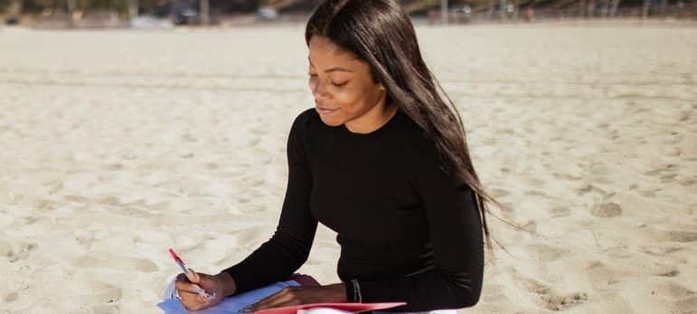 a woman sitting on the beach creating a plan for moving to Fisher Island