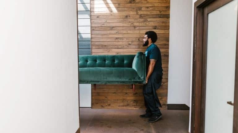 a man carrying green sofa