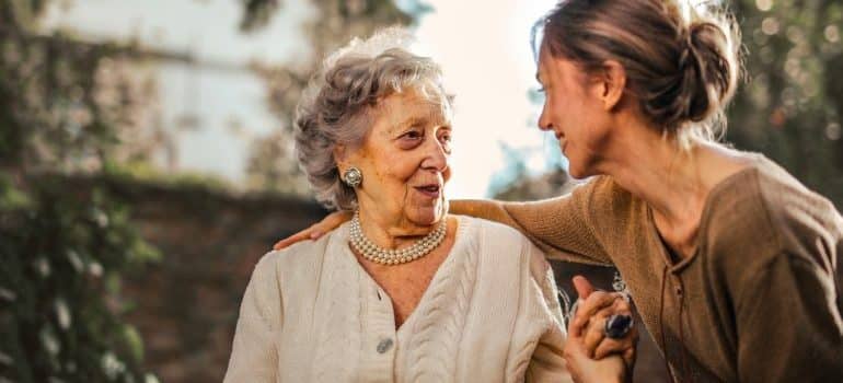 Elder woman with her daughter holding hands and talking.