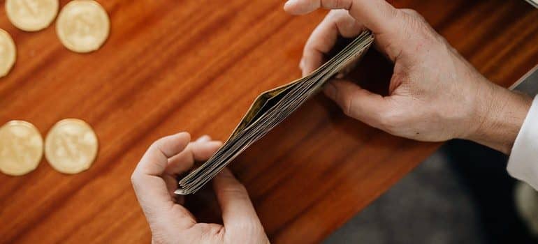 A pair of hands holding a stack of money on a table. 