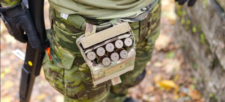 A picture of ammo in a belt case on a hunter in the woods.