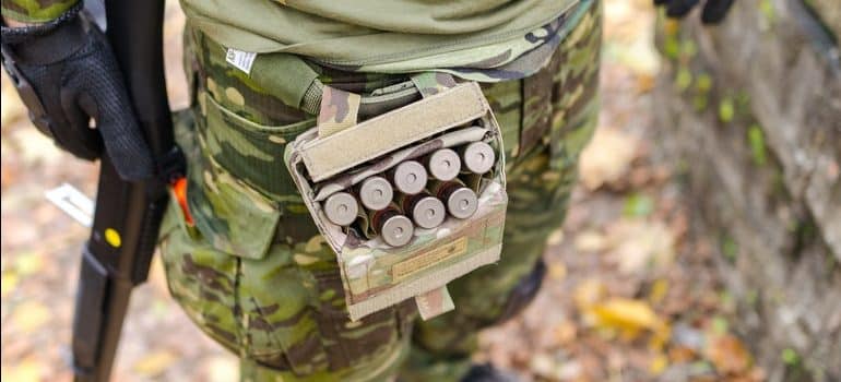 A picture of ammo in a belt case on a hunter in the woods.