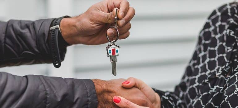 Close-up of male hands handing over house keys to women's hands.