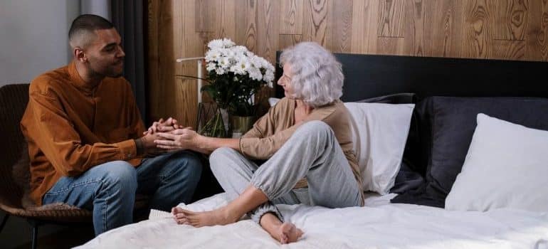 Younger man helping out a senior woman and talking to her.