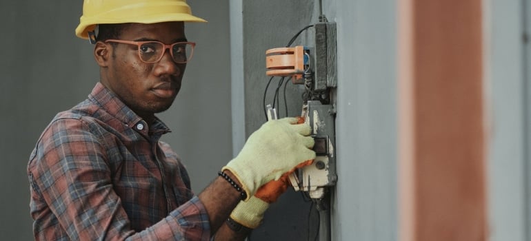 a man wearing protective gear while fixing the electricity to ensure that they can get settled after moving to Fort Lauderdale