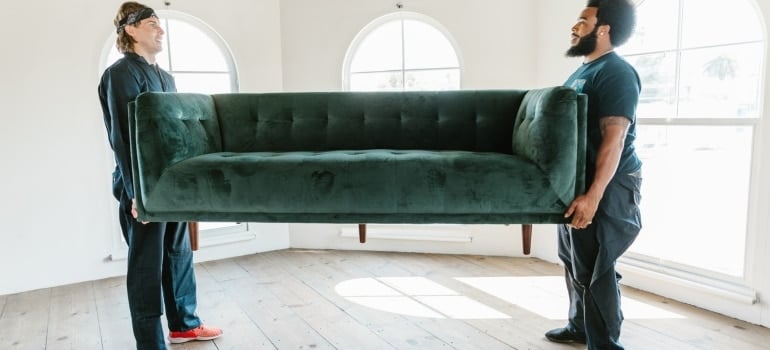 Professional movers carrying a green couch