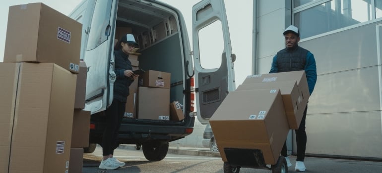 a moving crew loading cardboard boxes onto the dolly