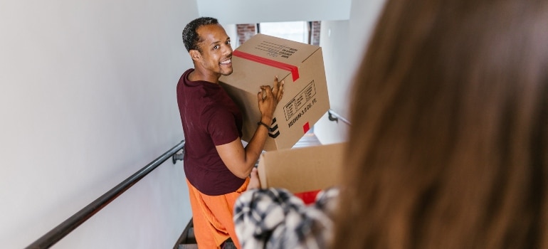 a smiling guy carrying moving box