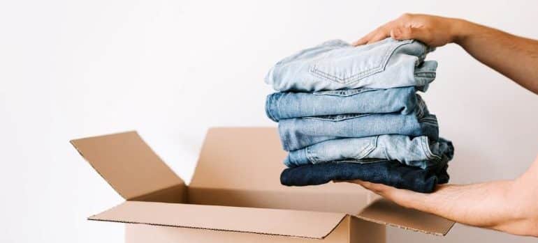 a person packing jeans in cardboard box