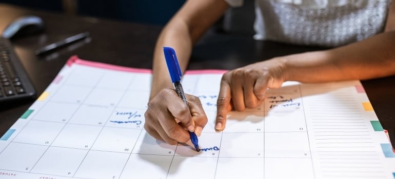 A person writing on a paper calendar