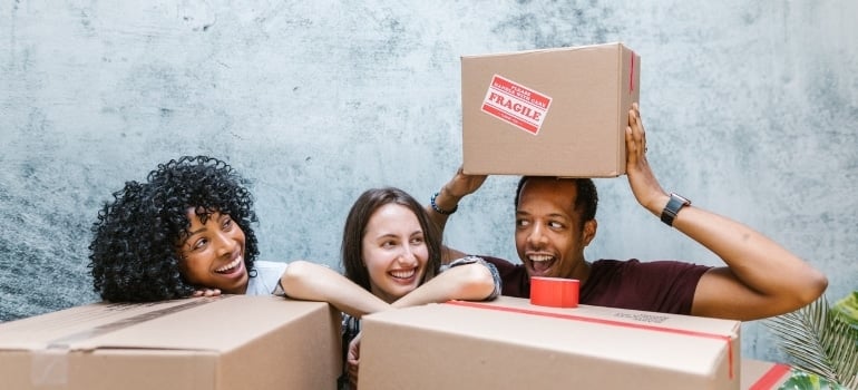 Women and man surrounded with moving boxes – doing residential and commercial relocation at the same time.
