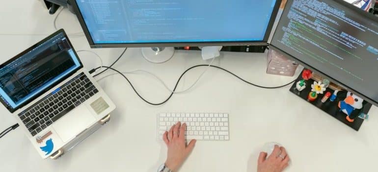 A person working in front of two screens and a laptop