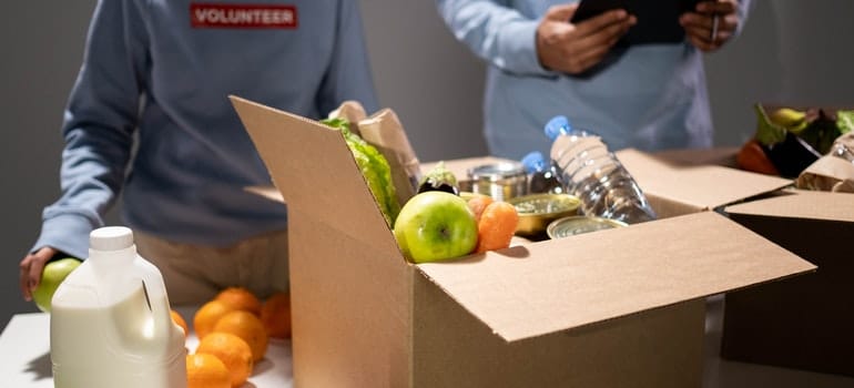 People are donating food in a box.