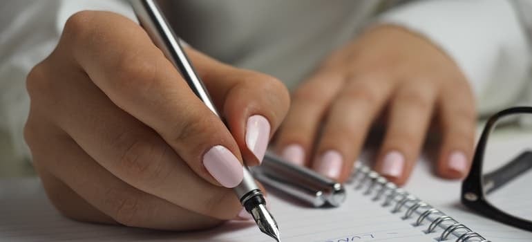 Woman holding a pen writing on a paper