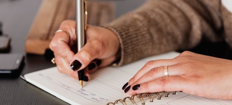 A woman thinking about ways to pack and transport heavy furniture from Kendall to Aventura while making a list. 