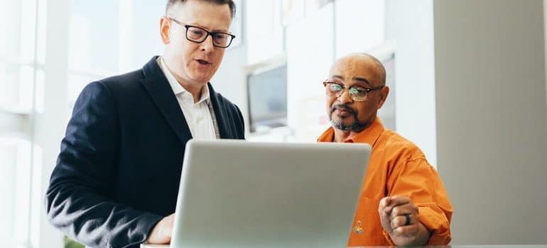 business man with laptop talking to another man