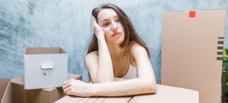 woman sitting around boxes holding her head