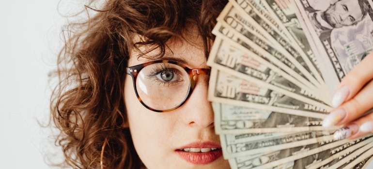 a woman covering her face with a fan made out of money