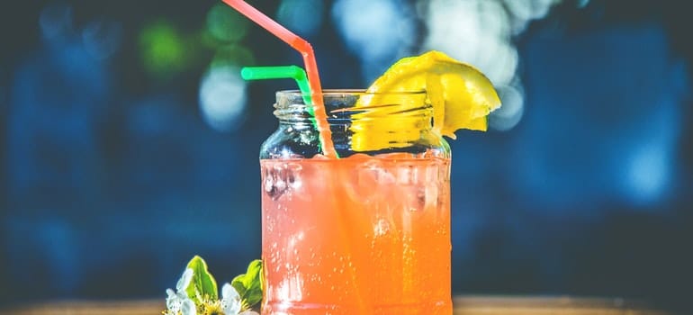 A jar full of juice on the table during a hot summer day.