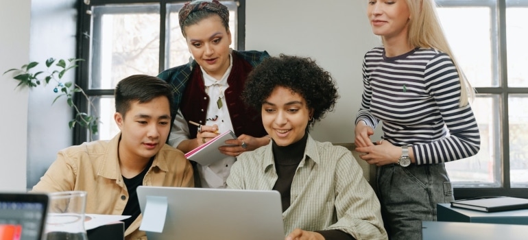 a group of team workers looking at a laptop