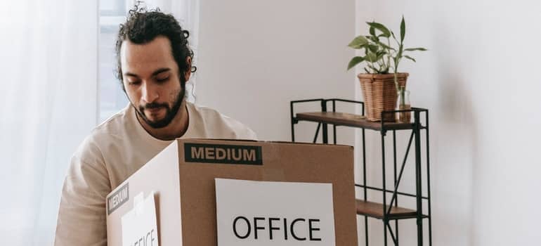 Man Carrying A Box With Office Sign