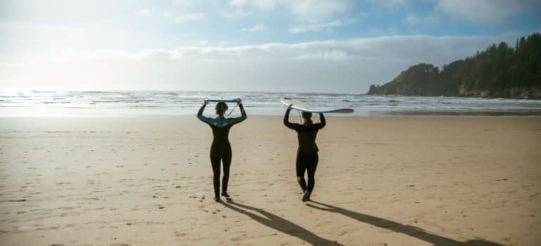 two people with surfboards on the beach