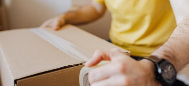 A person taping a moving box