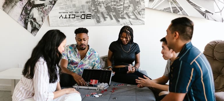 People are sitting on a bed and playing poker.