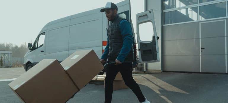 A mover using a dolly to transport insured moving boxes.