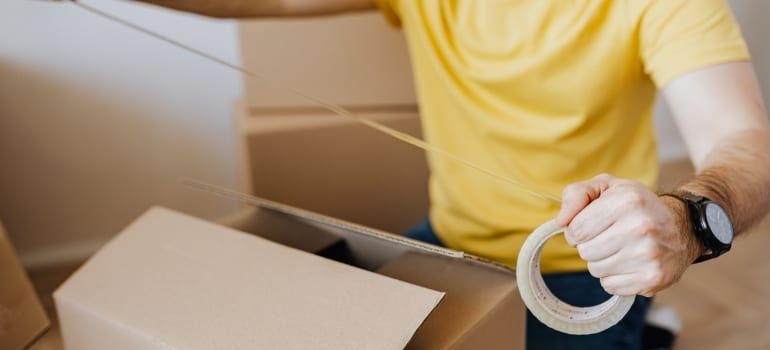 a man putting tape across a cardbord box