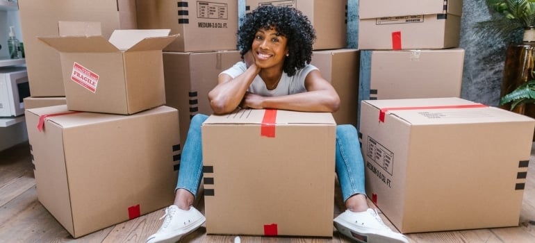 a woman sitting among moving boxes, smiling