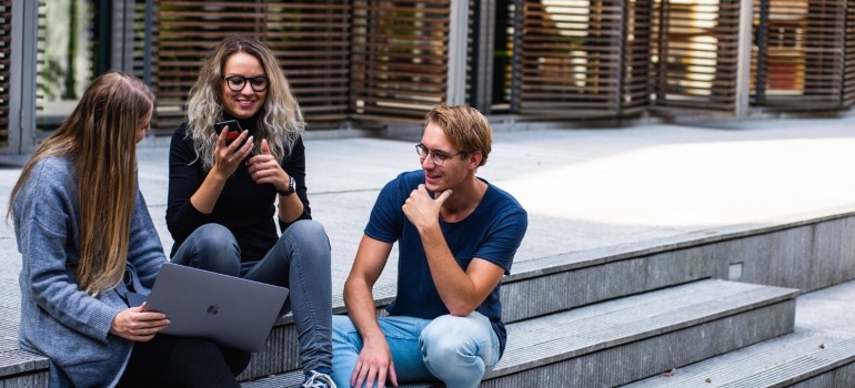 a group of students in front of a library, sitting on stairs