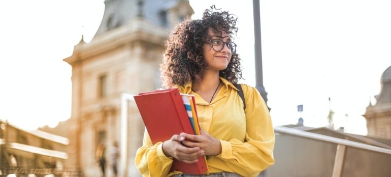 a young woman with books and notebooks on a street