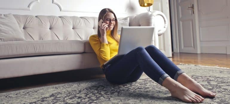 Woman on the phone in front of the laptop in her home