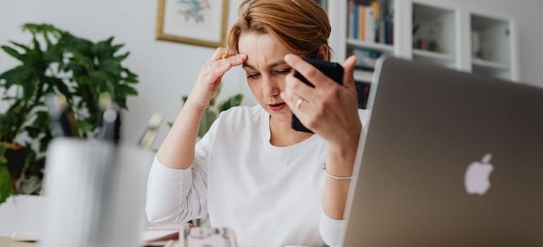 A woman holding her phone and touching her head