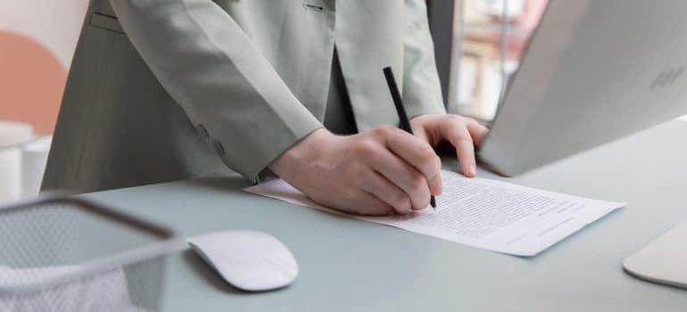 Woman signing a contract with shipping company before moving expensive household items long distance 