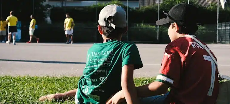 Two Boys Watching a Local Soccer Game Outdoors in one of the best school districts in Miami