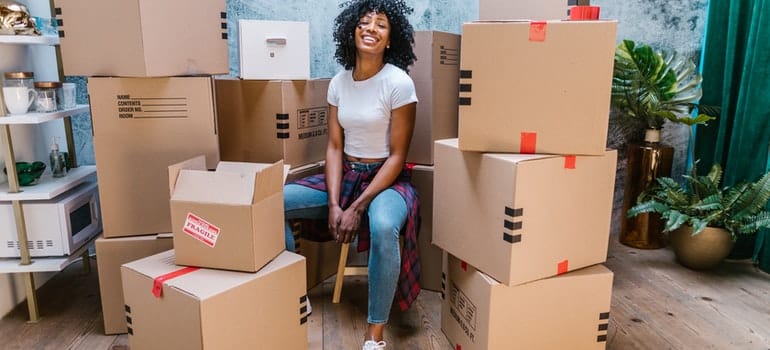 A woman is sitting surrounded by boxes.