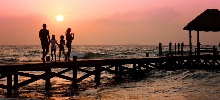 a family walking on a beach during sunset