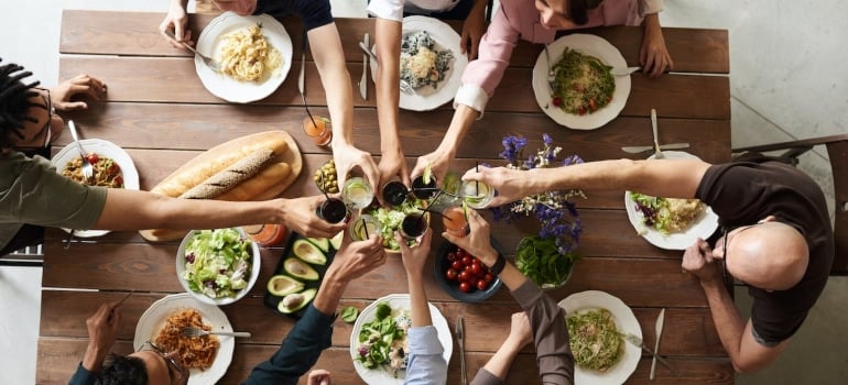 Table with food and hands with glasses above it