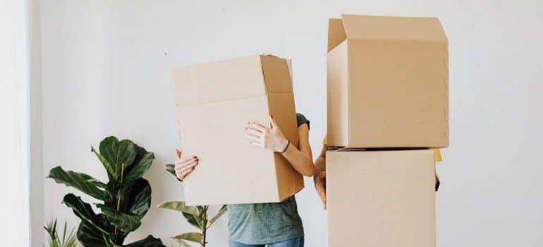 A man and woman holding boxes, their faces aren't seen.