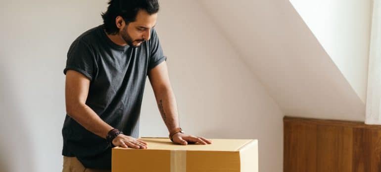 A man standing over a box preparing to take it outside preparing for a move in Marathon.