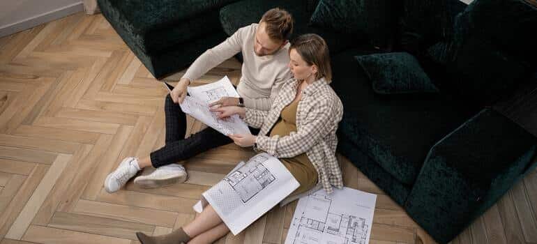 A couple is discussing Edgewater real estate prices over house blueprints