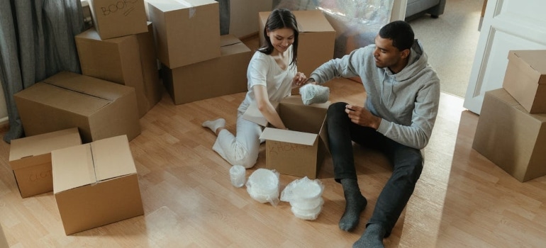 A woman and a man packing boxes. You may want to hire experts when moving your furniture to another state.