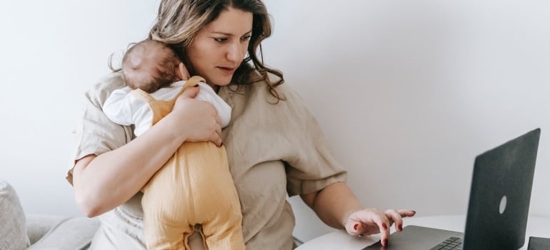 Woman holding a baby and working 