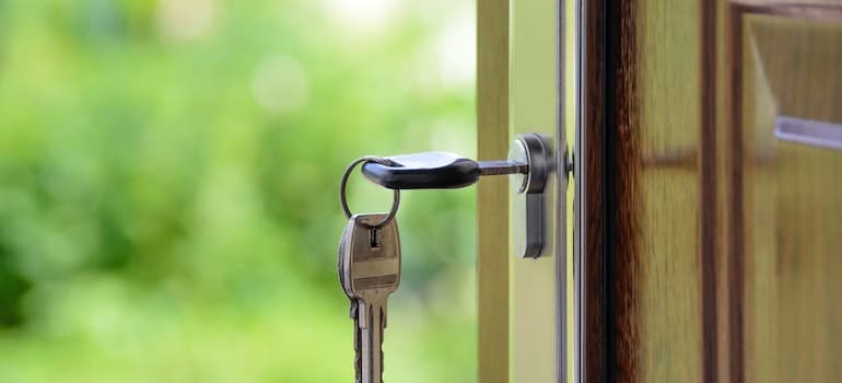 A key in the key hole on a door, symbolizing buying new a new property, something you'll need to think about when thinking whether to renovate or move your home in Fort Lauderdale.