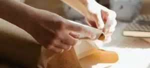 A hand is seen adding extra layers of protection to the object, which is one of the best possible things to do when packing oddly shaped objects for a long distance relocation.