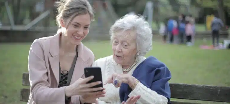 A cheerful senior mother and adult daughter using a smartphone together.