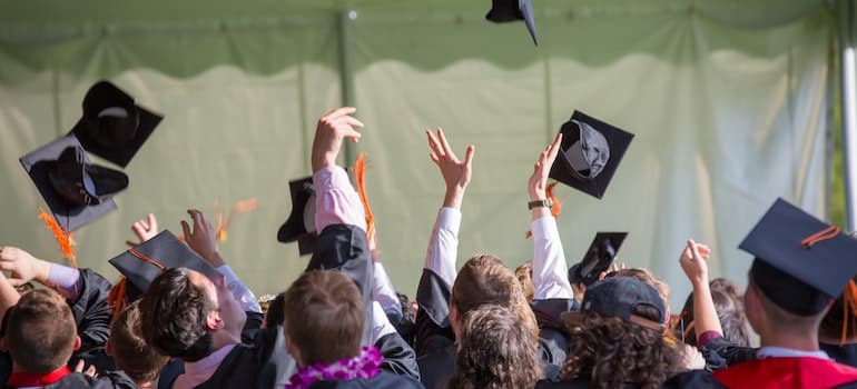 graduates throwing hats while thinking about pros and cons of living in Davie, FL;