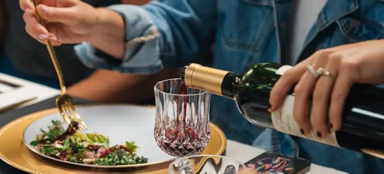 Woman pours red wine in wineglasses and eats salad in a restaurant.
